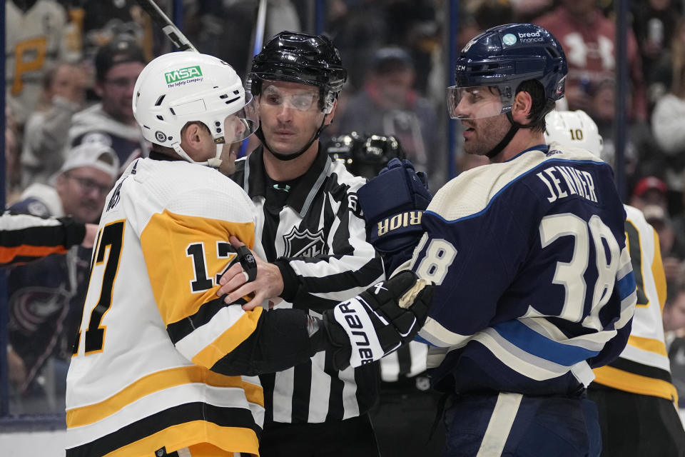 A linesman keeps Pittsburgh Penguins right wing Bryan Rust (17) and Columbus Blue Jackets center Boone Jenner (38) apart during the second period of an NHL hockey game Tuesday, Nov. 14, 2023, in Columbus, Ohio. (AP Photo/Sue Ogrocki)