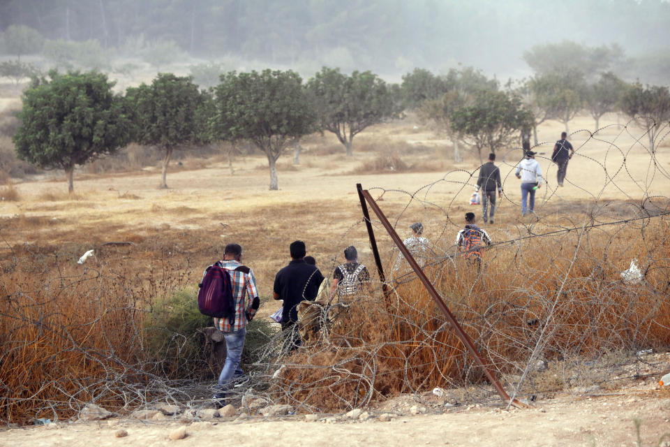 Palestinian laborers cross illegally into Israel from the West Bank through an opening in a fence near the West Bank town of Hebron, Sunday, Aug. 23, 2020. (AP Photo/Mahmoud Illean)