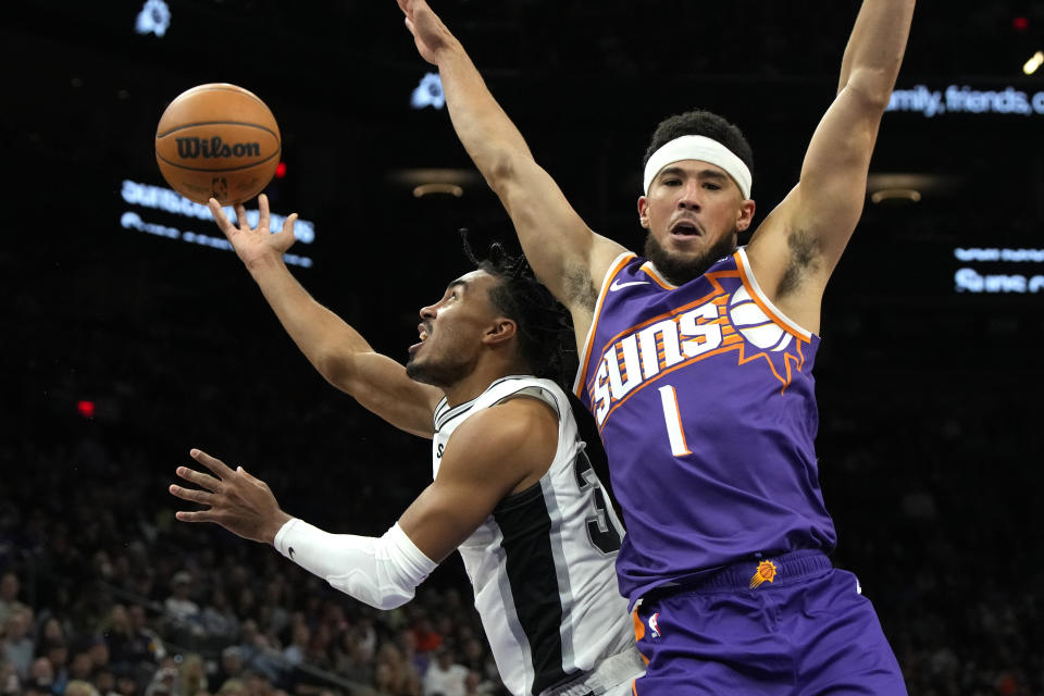San Antonio Spurs guard Tre Jones shoots next to Phoenix Suns guard Devin Booker (1) during the second half of an NBA basketball game Thursday, Nov 2, 2023, in Phoenix. (AP Photo/Rick Scuteri)