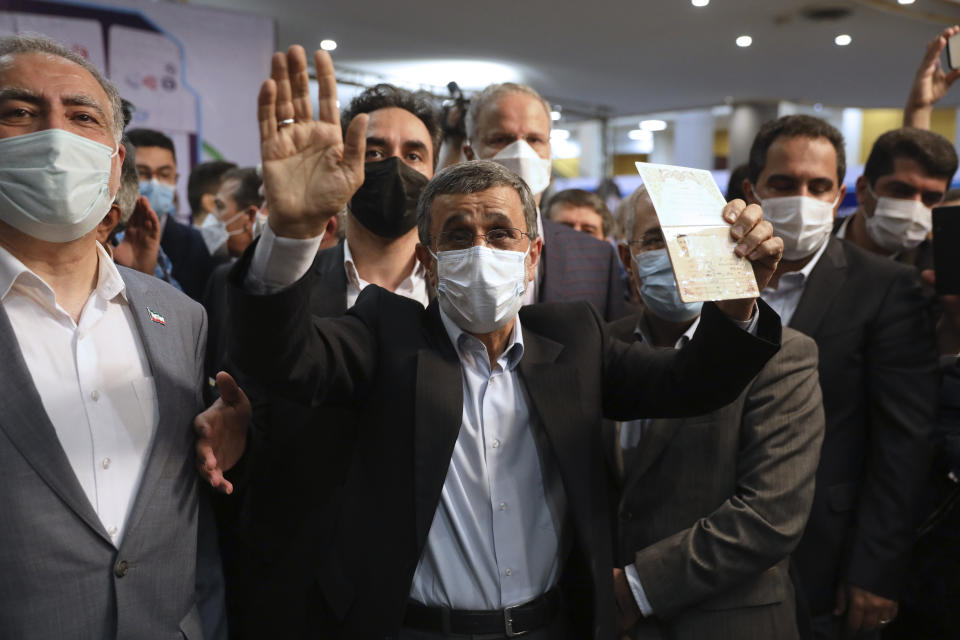 Former President Mahmoud Ahmadinejad, right, waves as he shows his identification document while registering his name as a candidate for the June 18, presidential elections at elections headquarters of the Interior Ministry in Tehran, Iran, Wednesday, May 12, 2021. The country's former firebrand president will run again for office in upcoming elections in June. The Holocaust-denying Ahmadinejad has previously been banned from running for the presidency by Supreme Leader Ayatollah Ali Khamenei in 2017, although then, he registered anyway. (AP Photo/Vahid Salemi)