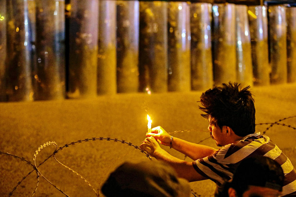 An anti-government protester lighting a candle while Security forces surround the protest site during ongoing protests in Basra, Iraq, Wednesday, Nov. 4, 2020. (AP Photo/Nabil al-Jurani)