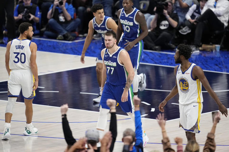 Dallas Mavericks guard Luka Doncic (77) celebrates after sinking a basket as Golden State Warriors' Stephen Curry (30) and Andrew Wiggins look on in the second half of an NBA basketball game in Dallas, Tuesday, Nov. 29, 2022. (AP Photo/Tony Gutierrez)