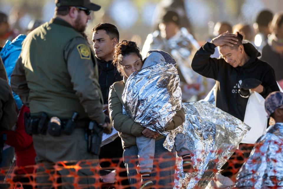 A US Border Patrol agent watches as migrants arrive at a transit centre near the US-Mexico border in Texas on 19 December. (Getty Images)