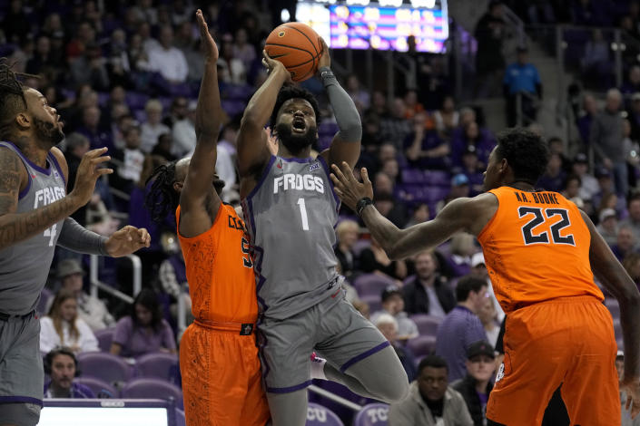 TCU guard Mike Miles Jr. (1) takes a shot between Oklahoma State's John-Michael Wright, center left, and Kalib Boone (22) as Eddie Lampkin Jr., left, looks on in the second half of an NCAA college basketball game, Saturday, Feb. 18, 2023, in Fort Worth, Texas. (AP Photo/Tony Gutierrez)