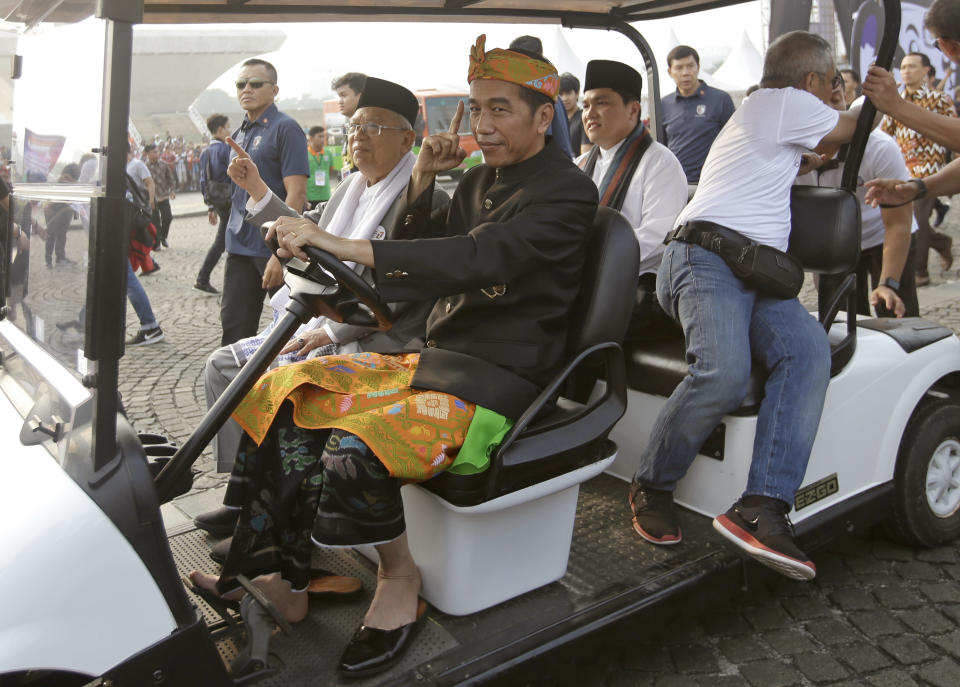 Indonesian President Joko Widodo, center right, rides a golf cart and his running mate Ma'ruf Amin during a ceremony marking the kick off of the campaign period for next year's election in Jakarta, Indonesia, Sunday, Sept. 23, 2018. Indonesia is set to hold its presidential and parliamentary election poll in April 2019.(AP Photo/Tatan Syuflana)