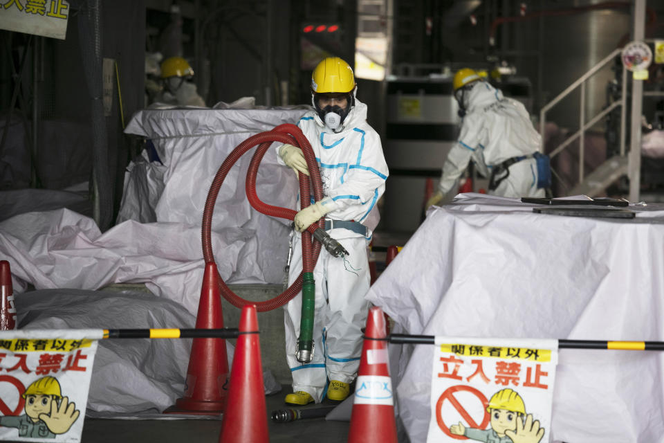FILE - In this Feb. 12, 2020, file photo, a worker in a hazmat suit carries a hose while working at a water treatment facility at the Fukushima Dai-ichi nuclear power plant in Okuma, Fukushima Prefecture, Japan. Japanese Prime Minister Yoshihide Suga said Wednesday, Oct. 28, that his government is carefully working on final details on a release of the massive amount of treated but still radioactive water from the wrecked Fukushima nuclear plant, after a speculated decision of a release to the sea by the end of October has triggered fierce protests from fishermen around the country. (AP Photo/Jae C. Hong, File)