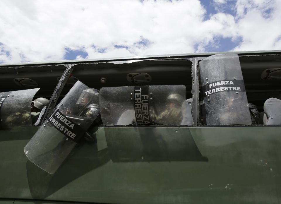 Soldiers sit inside a bus with its windows busted out in Oton, Ecuador, Friday, Oct. 4, 2019, during a nationwide transport strike that shut down taxi, bus and other services in response to a sudden rise in fuel prices. Ecuador's President Lenín Moreno, who earlier declared a state of emergency over the strike, vowed Friday that he wouldn't back down on the decision to end costly fuel subsidies, which doubled the price of diesel overnight and sharply raised gasoline prices. (AP Photo/Dolores Ochoa)