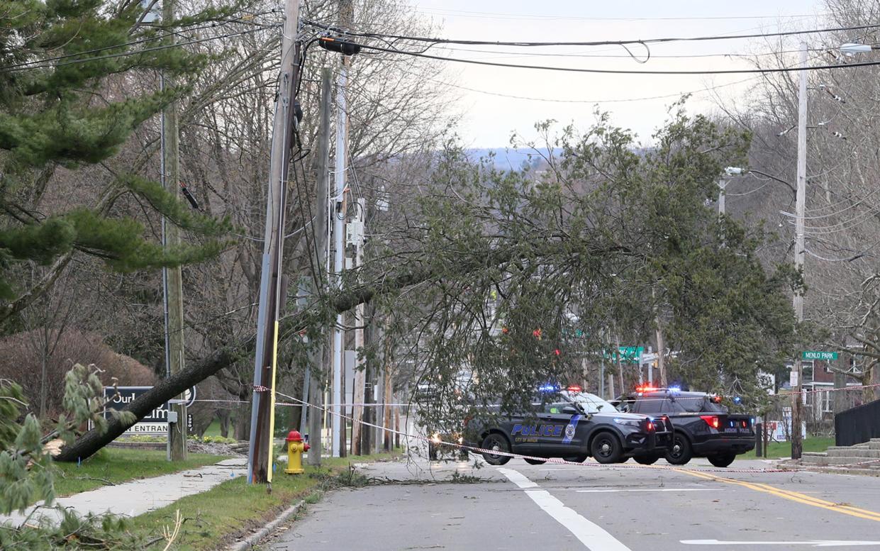 Police block West Market Street between Twin Oaks Road and Menlo Park Drive on Saturday in Akron as an uprooted tree hangs on wires over the road.