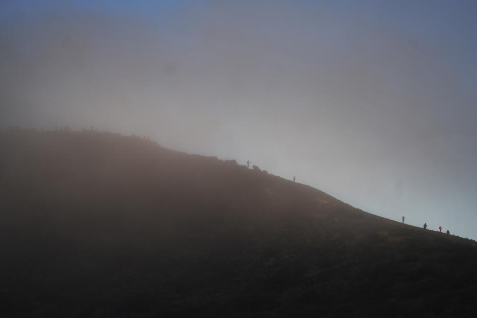 Visitors walk through the clouds at 9,000 feet elevation on the sacred mountain of Mauna Kea in Hawaii on Saturday July, 15, 2023. (AP Photo/Jessie Wardarski)