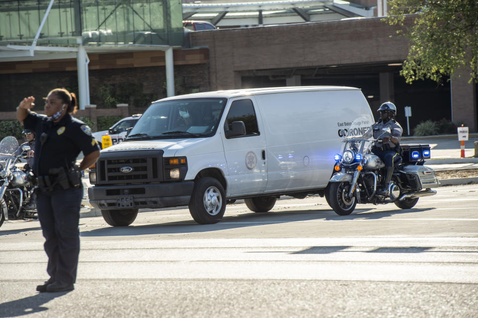 An officer salutes a motorcycle escort and a coroner's van carrying the body of a Baton Rouge police officer who was fatally shot, Sunday afternoon, April 26, 2020, in Baton Rouge, La. The shooting left one police officer dead and a wounded colleague fighting for life Sunday, authorities said, adding a suspect was in custody after an hourslong standoff at a home. Baton Rouge Police Chief Murphy Paul told The Advocate the officers were shot in the northern part of the city, and one of the officers later died. (John Ballance/The Advocate via AP)