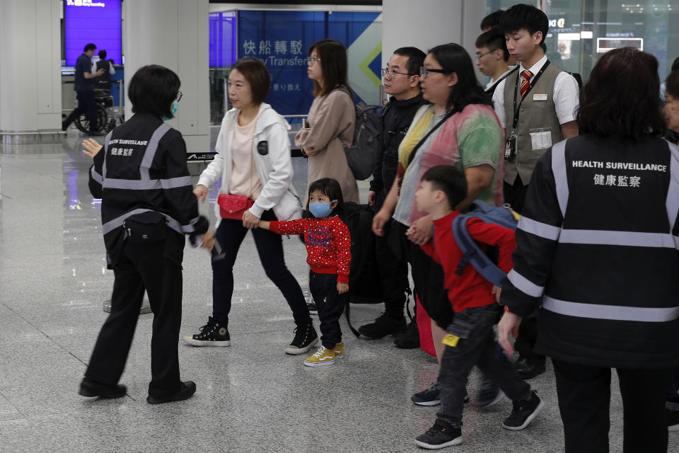 Health surveillance officer use device to check temperature of passengers before the immigration counters at International airport in Hong Kong, Saturday, Jan. 4, 2020. Hong Kong authorities activated a newly created "serious response" level Saturday as fears spread about a mysterious infectious disease that may have been brought back by visitors to a mainland Chinese city. (AP Photo/Andy Wong)