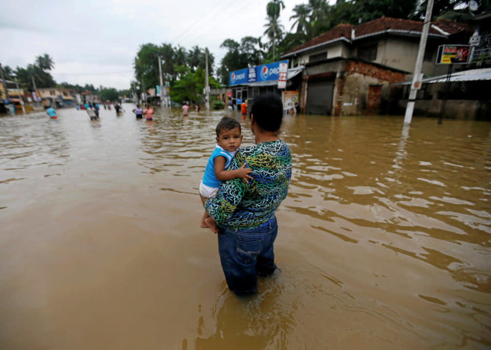 A mother and child on a flooded road in Biyagama, Sri Lanka, May 17, 2016. (Reuters/Dinuka Liyanawatte)