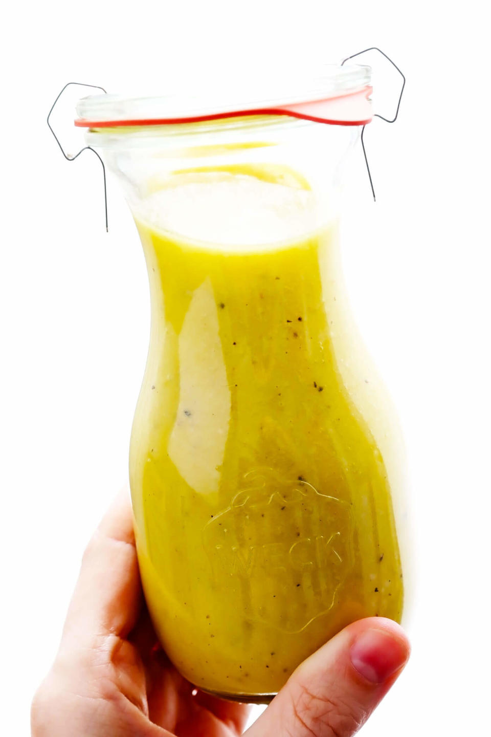 Hands holding a jar of homemade dressing.