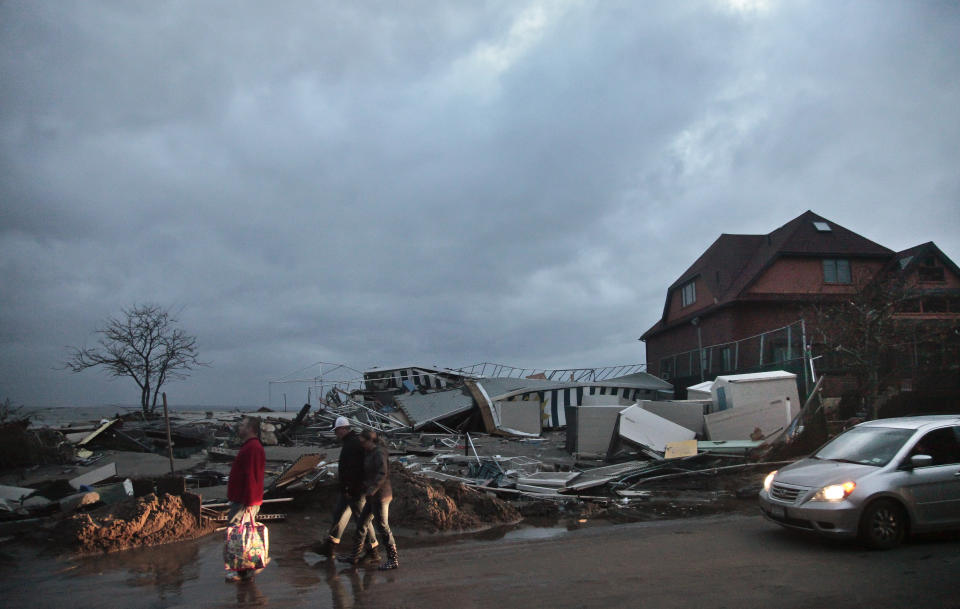 People walk through the houses destroyed in the aftermath of yesterday's storm surge from superstorm Sandy, Tuesday, Oct. 30, 2012, in Coney Island's Sea Gate community in New York. (AP Photo/Bebeto Matthews)