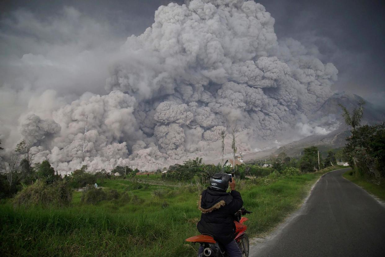 An Indonesian man takes a snap of Mount Sinabung as it spews thick volcanic ash into the air: AFP/Getty Images