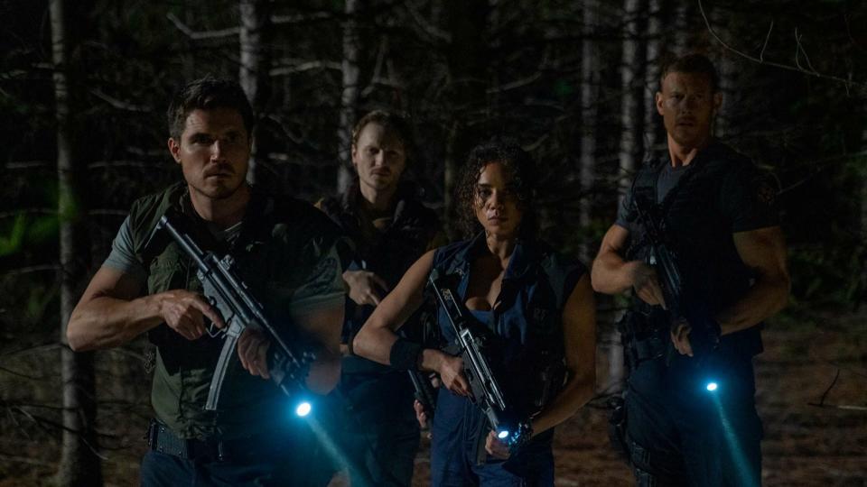 A still from Resident Evil: Welcome to Raccoon City shows the RCPD team holding guns in a forest