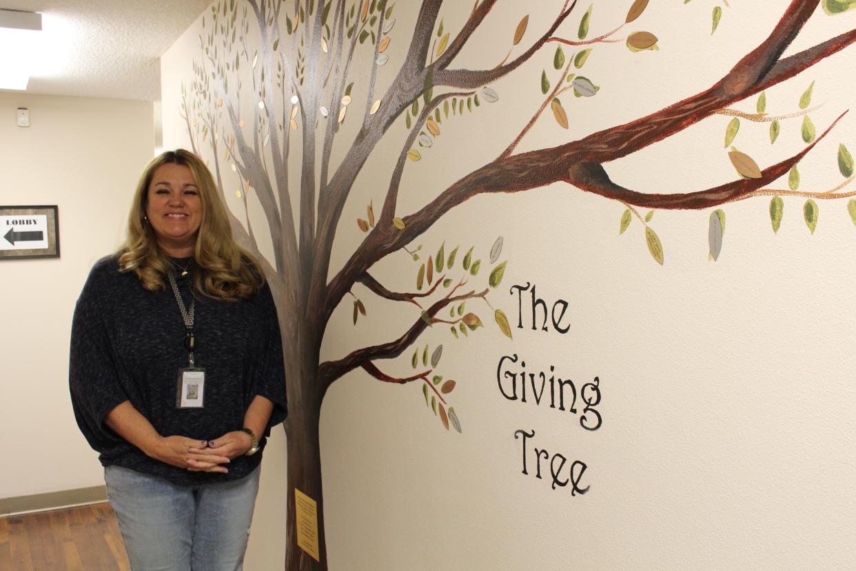 Patti Kimbrough, executive director of the Good Samaritan Clinic, stands in front of the Giving Tree, which recognizes those who donate time, talent and resources to the clinic.