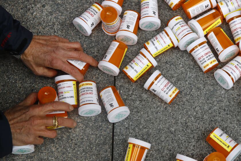 FILE - A protester gathers containers that look like OxyContin bottles at an anti-opioid demonstration in front of the U.S. Department of Health and Human Services headquarters in Washington on April 5, 2019. A California judge has ruled for top drug manufacturers as local governments seek billions of dollars to cover their costs from the nation's opioid epidemic. Orange County Superior Court Judge Peter Wilson issued a tentative ruling Monday, Nov. 1, 2021, that said the governments hadn't proven the pharmaceutical companies used deceptive marketing to increase unnecessary opioid prescriptions and create a public nuisance. (AP Photo/Patrick Semansky, File)