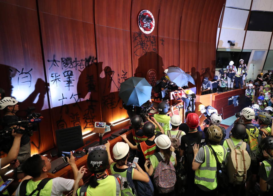 Members of the press take pictures of protesters defacing the Bauhinia Flower emblem of Hong Kong after breaking into the main chamber of the Legislative Council building. Source: AAP/RITCHIE B. TONGO