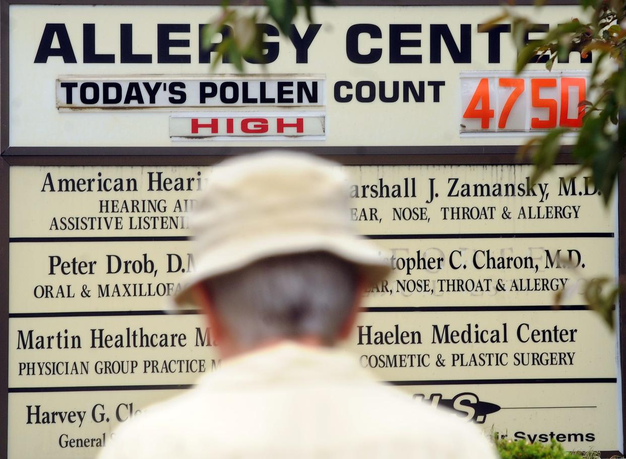 In a file photo, a man walks along Pleasant Street in Worcester past the Allergy Center sign, which displays the daily pollen count.