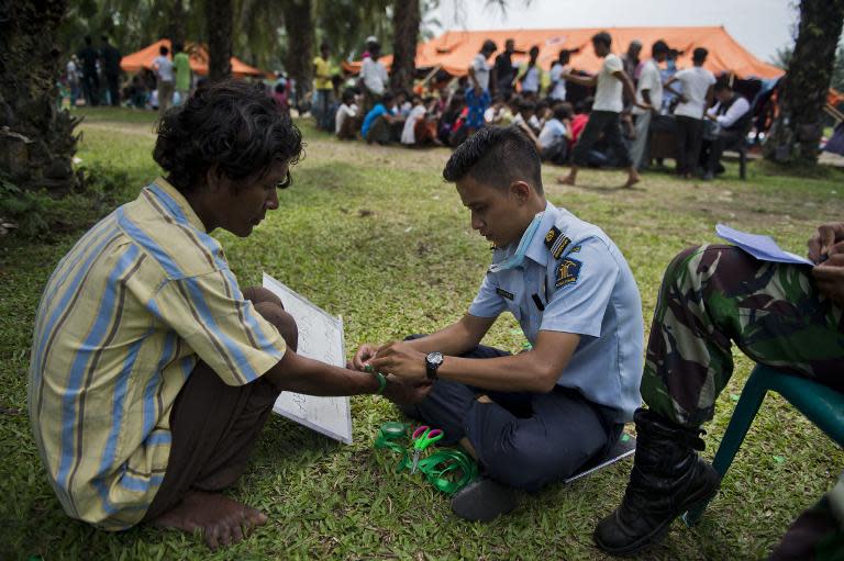 An Indonesian immigration officer marks a Rohingya man from Myanmar during documentation procedures at a new confinement area in Bayeun, Aceh province on May 21, 2015