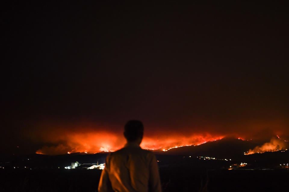 Man standing roadside watching fire