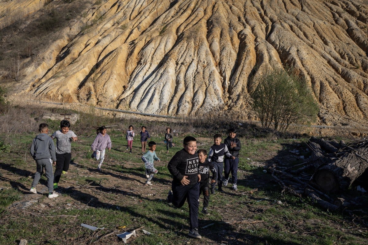 Children play in front of tailings at the Zmajevo settlement (Reuters)