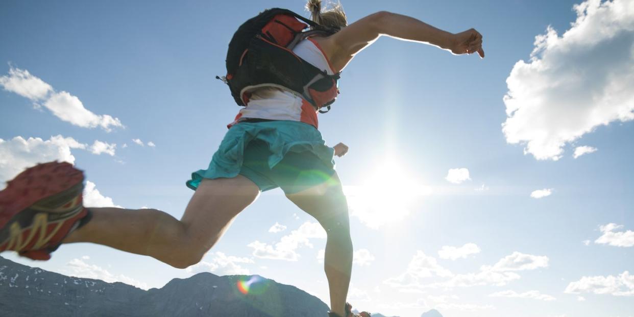 trail runner bounds along mountain ridge crest