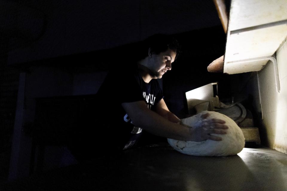 A pizza maker uses battery powered lamps to illuminate his work space during a blackout inside the delivery-only pizza shop in Buenos Aires, Argentina, Sunday, June 16, 2019. A widespread power failure early Sunday morning left a large section of South America, including all of Argentina and Uruguay, without power. AP Photo/Tomas F. Cuesta)