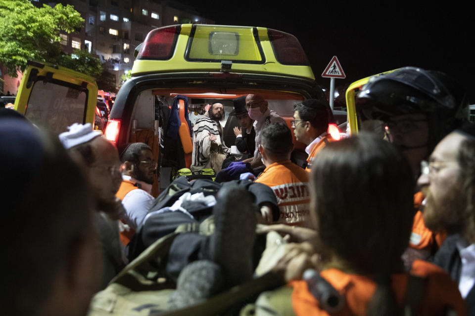 Israeli medics carry wounded ultra-Orthodox men outside a synagogue in Givat Zeev, outside Jerusalem, Sunday, May 16, 2021. Israeli medics say more than 150 people were injured in a fatal collapse of a bleacher at an uncompleted West Bank synagogue. (AP Photo/Sebastian Scheiner)