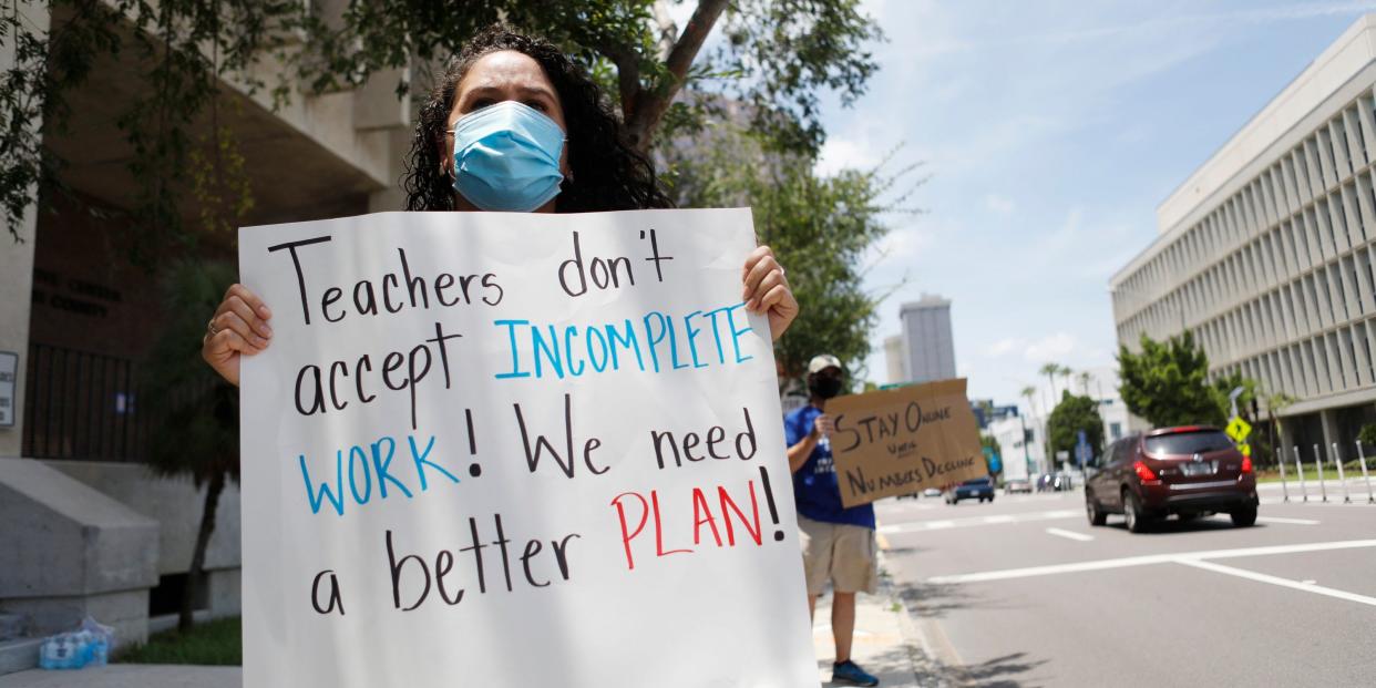 First grade teacher Yolanda Vasquez (R) stands in protest along with other teachers and counselors in front of the Hillsborough County Schools District Office on July 16, 2020 in Tampa, Florida. Teachers and administrators from Hillsborough County Schools rallied against the reopening of schools due to health and safety concerns amid the COVID-19 pandemic.