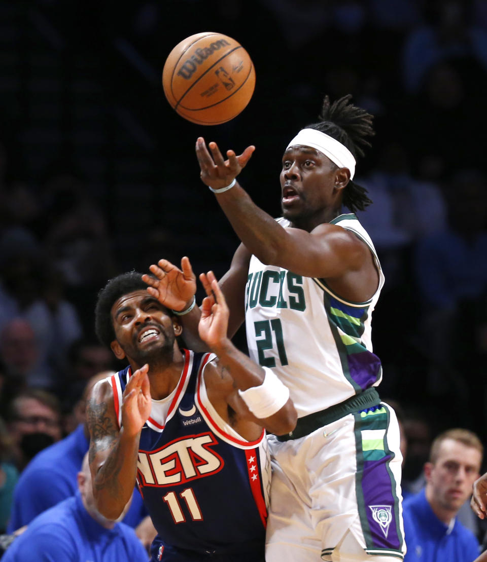 Milwaukee Bucks guard Jrue Holiday (21) reaches for the ball next to Brooklyn Nets guard Kyrie Irving (11) during the first half of an NBA basketball game Thursday, March 31, 2022, in New York. (AP Photo/Noah K. Murray)