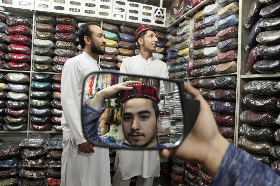 A man tries on a traditional cap in preparation for the upcoming Muslim fasting month of Ramadan, in Peshawar, Pakistan, Saturday, April 2, 2022. The Muslim holy month of Ramadan — when the faithful fast from dawn to dusk — began at sunrise Saturday in much of the Middle East, where Russia's invasion of Ukraine has sent energy and food prices soaring. (AP Photo/Muhammad Sajjad)