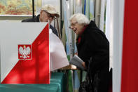 Voters inspect ballots at a polling station in Warsaw, Poland, Sunday, Oct. 13, 2019. Poles are voting Sunday in a parliamentary election, that the ruling party of Jaroslaw Kaczynski is favored to win easily, buoyed by the popularity of its social conservatism and generous social spending policies that have reduced poverty. (AP Photo/Darko Bandic)
