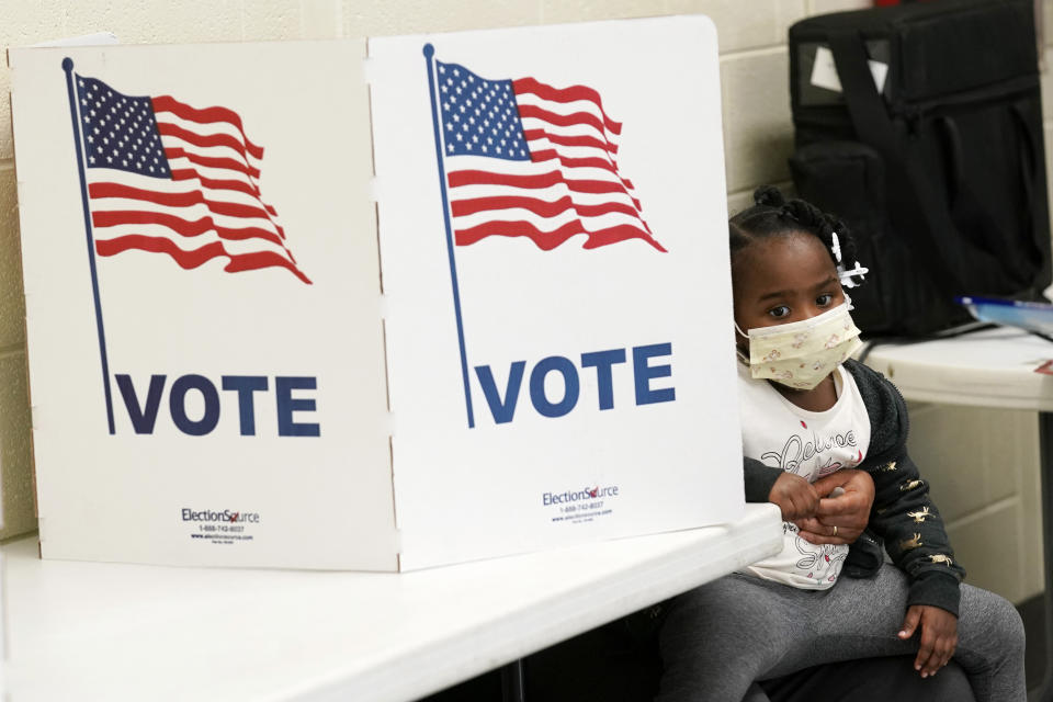 FILE - Mikara Stewart, 5, looks around a voting privacy kiosk while her grandmother, Doris Thomas, obscured, votes in Precinct 36 after standing in line for almost two hours in Jackson, Miss., on Nov. 3, 2020. In the wake of the proposed House Bill 1020, Black lawmakers say creating courts with appointed judges would strip away voting rights in a state where older generations of Black people still remember the struggle for equal access to the ballot. (AP Photo/Rogelio V. Solis, File)