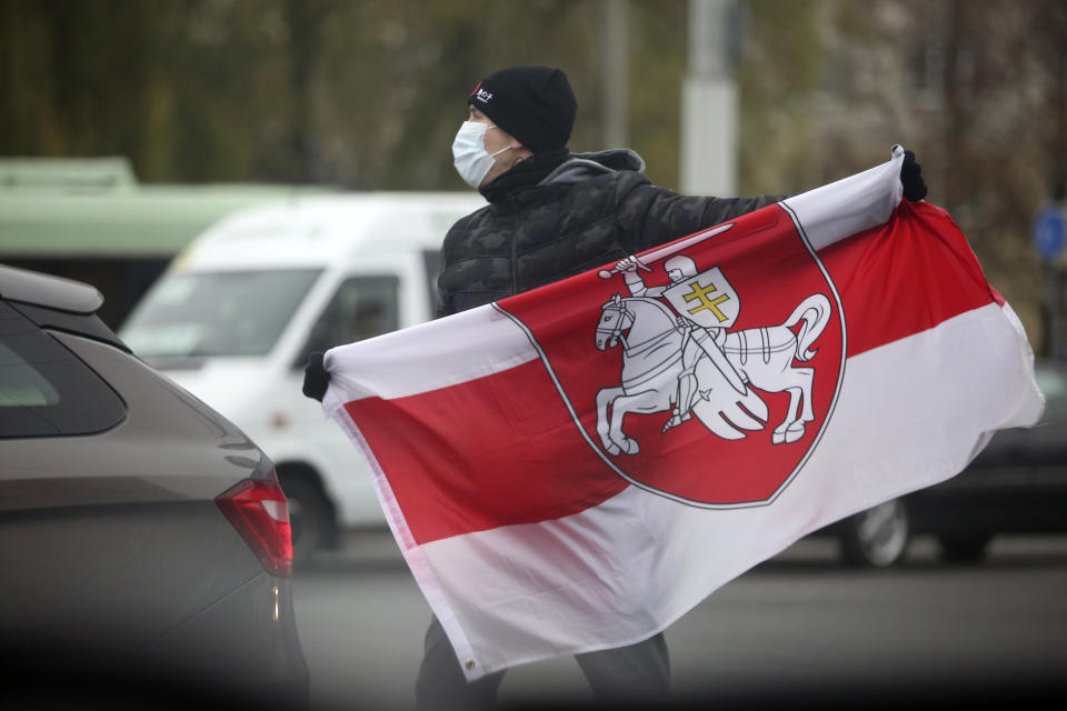 A man wearing a face mask to help curb the spread of the coronavirus holds an old Belarusian national flag during an opposition rally to protest the official presidential election results in Minsk, Belarus, Sunday, Nov. 22, 2020. The Belarusian human rights group Viasna says more than 140 people have been arrested and many of them beaten by police during protests calling for the country's authoritarian president to resign. The demonstrations that attracted thousands were the 16th consecutive Sunday of large protests against President Alexander Lukashenko. (AP Photo)