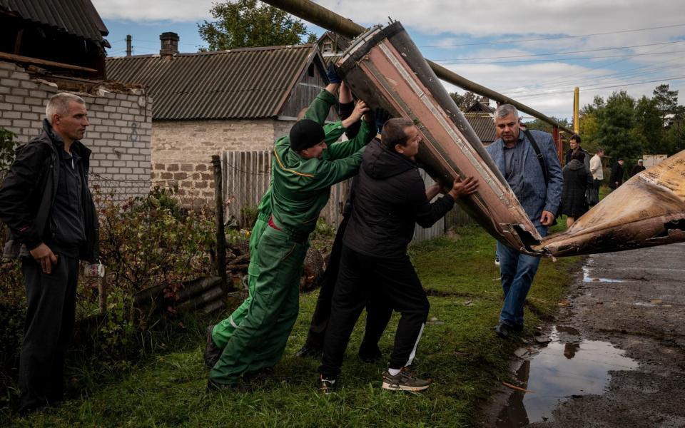 Municipal workers remove the remnants of a missile that hit overnight from the garden of a residence in Kramatorsk - Nicole Tung/The New York Times