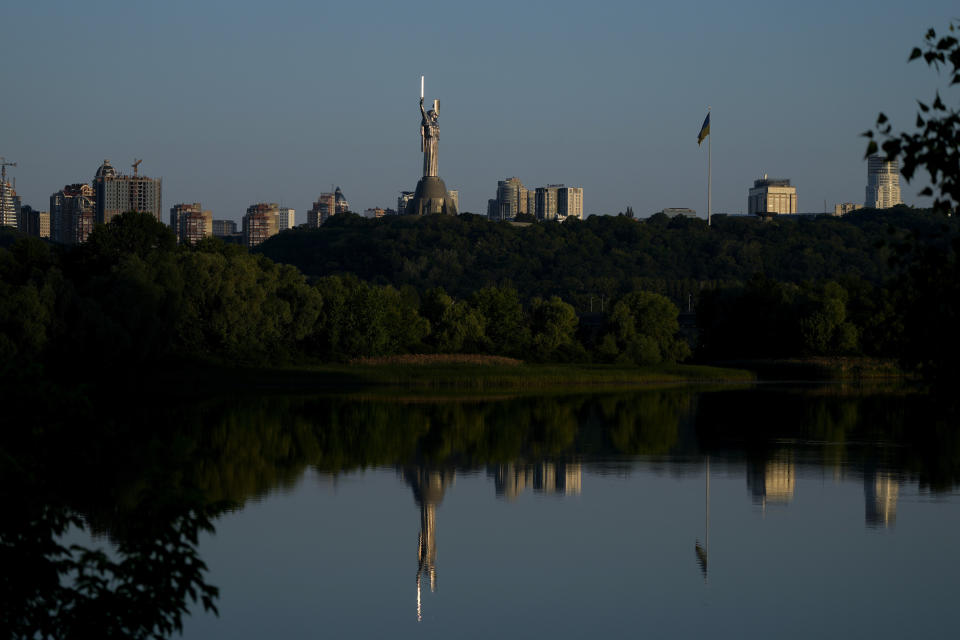 The Motherland Monument is reflected on the Dnieper River in Kyiv, Ukraine, Friday, June 10, 2022. With war raging on fronts to the east and south, the summer of 2022 is proving bitter for the Ukrainian capital, Kyiv. The sun shines but sadness and grim determination reign. (AP Photo/Natacha Pisarenko)