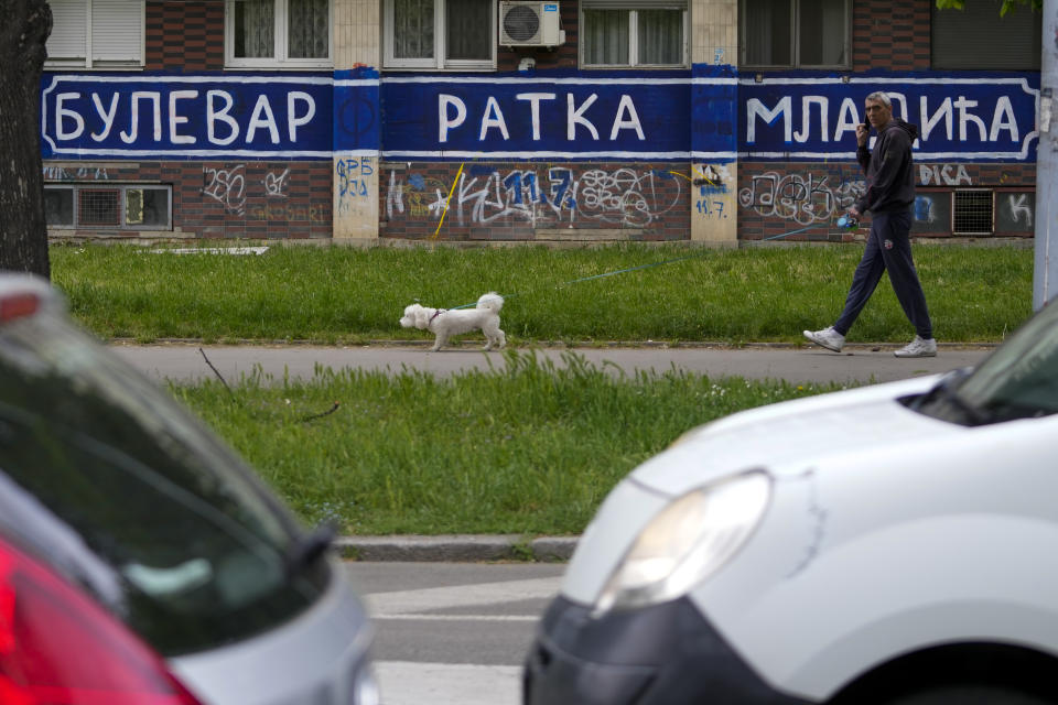 A man with a dog walks by a mural reading ''Boulevard Ratko Mladic" in Belgrade, Serbia, Tuesday, May 9, 2023. The avenue is not officially named after the Bosnian Serb general who was convicted of genocide by an international court for war crimes committed by his troops during the clashes in the Balkans in the 1990s. It carries the name of Serbia's first pro-Western Prime Minister Zoran Djindjic who was gunned down by a sniper bullet in front of his government's offices in Belgrade on March 12, 2003. (AP Photo/Darko Vojinovic)
