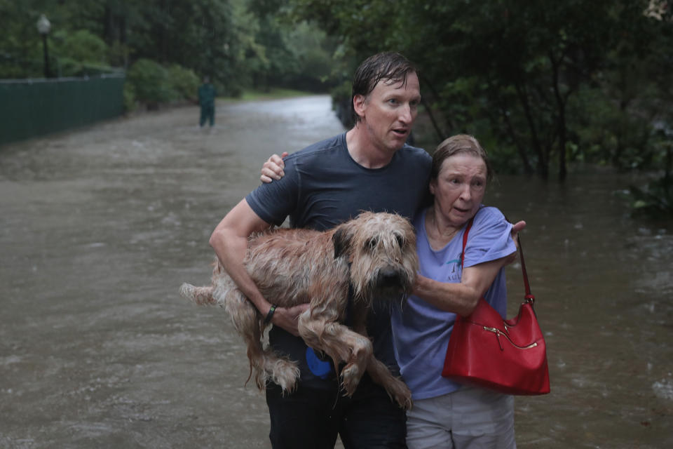 <p>Andrew White (L) helps a neighbor down a street after rescuing her from her home in his boat in the upscale River Oaks neighborhood after it was inundated with flooding from Hurricane Harvey on Aug. 27, 2017 in Houston, Texas. (Photo: Scott Olson/Getty Images) </p>