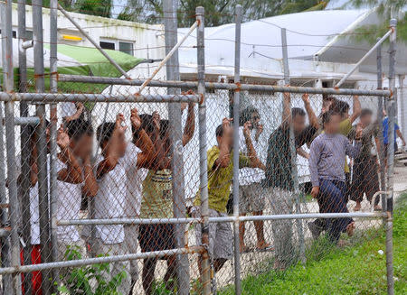 Asylum-seekers look through a fence at the Manus Island detention centre in Papua New Guinea March 21, 2014. Faces pixellated at source. Picture taken March 21, 2014. Eoin Blackwell/AAP/via REUTERS