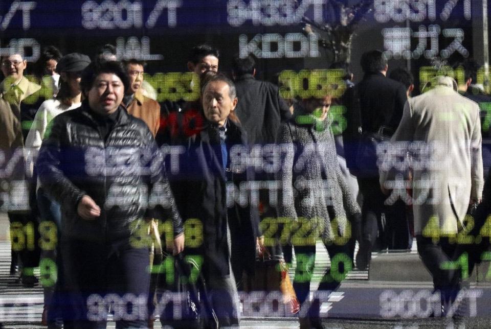 People are reflected on an electronic stock indicator of a securities firm in Tokyo, Tuesday, Jan. 17, 2017. Asian stocks declined Tuesday after Britain said Prime Minister Theresa May will announce London's plans to withdraw completely from the European Union. (AP Photo/Shizuo Kambayashi)