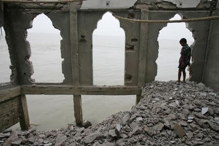 A boy looks at the River Padma at a Muslim shrine under threat from erosion of the river in Shariatpur, June 23, 2008. The banks along Bangladesh's major river are eroding following heavy monsoon rains. REUTERS/Andrew Biraj