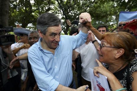 Francois Fillon (L), former French prime minister, member of The Republicans political party and 2017 presidential candidate of the French centre-right, shakes hands with a supporter while attending a picnic in Saint-Paul as he campaigns on the French Indian Ocean island of the Reunion, February 12, 2017. REUTERS/Laurent Capmas