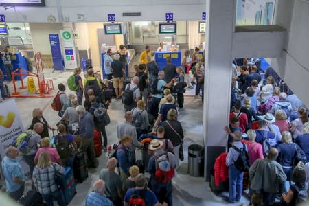 People line up in front of a counter of Thomas Cook at the Heraklion airport on the island of Crete