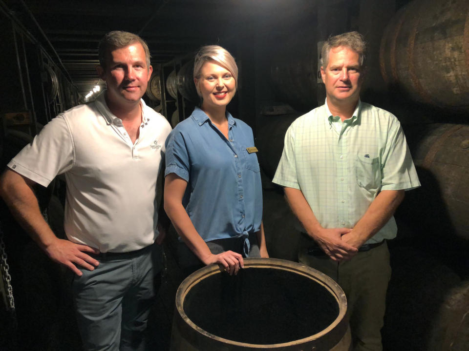 In this Friday, Sept. 14, 2018 photo, master distiller Marianne Eaves, center, is flanked by co-owners Will Arvin, right, and Wes Murray, while posing in a barrel warehouse Castle & Key Distillery in Millville, Ky. The group were behind the restoration of the Old Taylor distillery which is now known as Castle & Key Distillery. Eaves hopes rye can make its debut in about a year, and says the brand’s bourbon could be ready in 2021. (AP Photo/Bruce Schreiner)