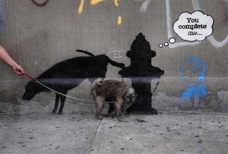 A dog urinates on a new work by British graffiti artist Banksy on West 24th street in New York City, October 3, 2013. REUTERS/Mike Segar