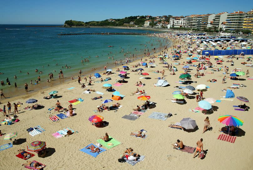 People wearing face masks to protect against coronavirus, walk the streets of Saint Jean de Luz, southwestern France, Thursday, Aug. 5, 2020.