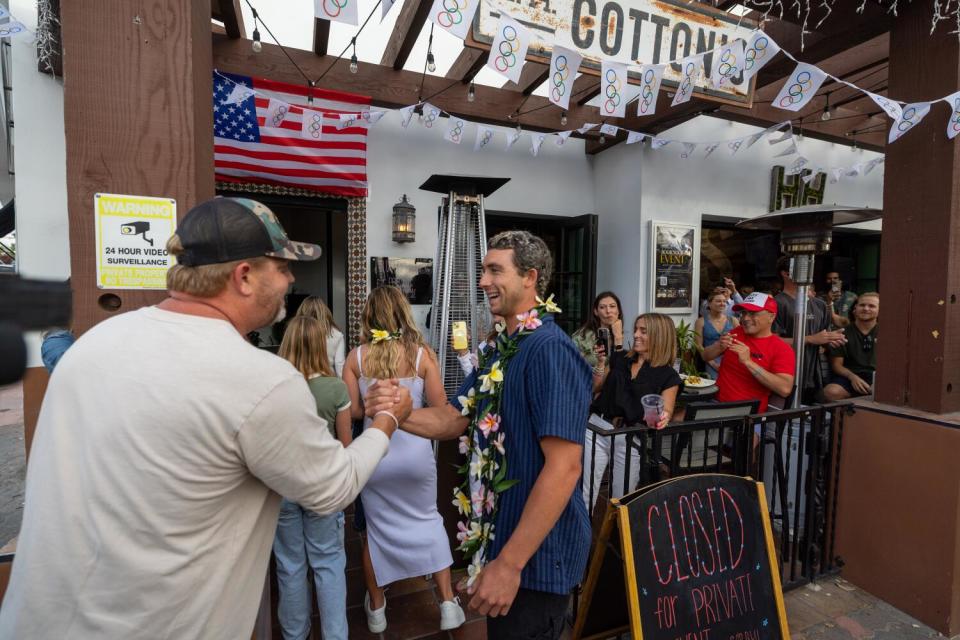 Jake Howard, left, editor-in-chief of Surfer Magazine, shakes hands with U.S. Olympic surfer Griffin Colapinto.