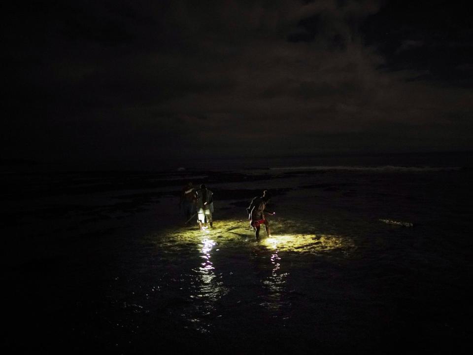 People fish for crabs at night using flashlights on the coast of the Pacific Ocean on December 05, 2019 in Tanna, Vanuatu.